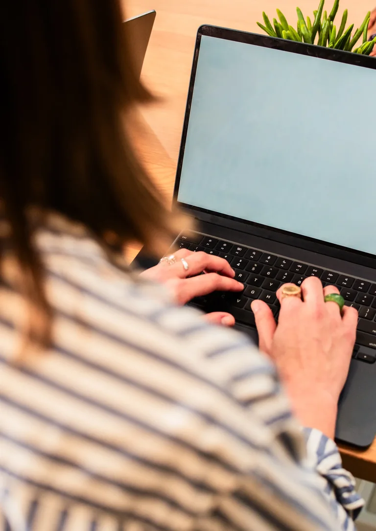 Profissional trabalhando em notebook sobre mesa de madeira com luz natural